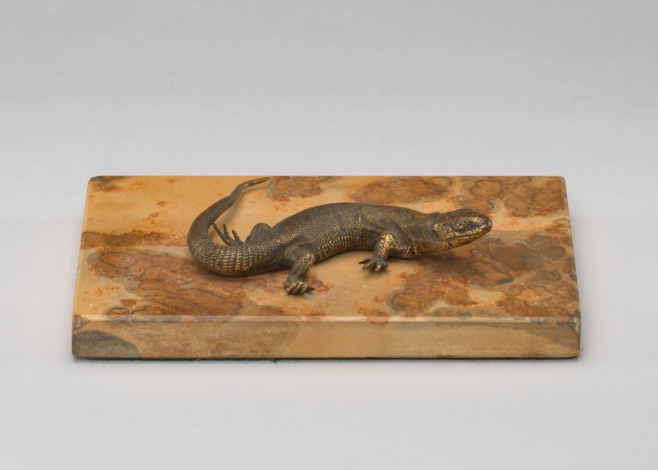 A bronze cast of a lizard mounted on marble.